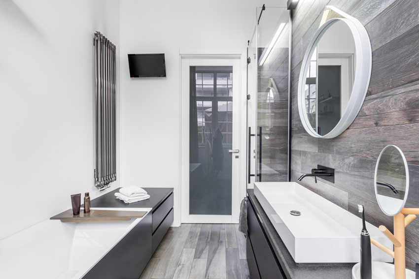 Salle de bain longue et étroite, carrelage effet bois gris.