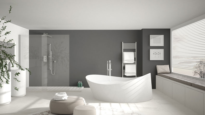 Salle de bain moderne avec murs gris et baignoire blanche.