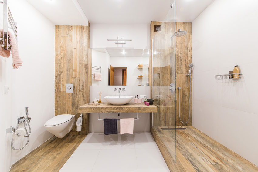 Petite salle de bain bien meublée en longueur, revêtement effet bois.