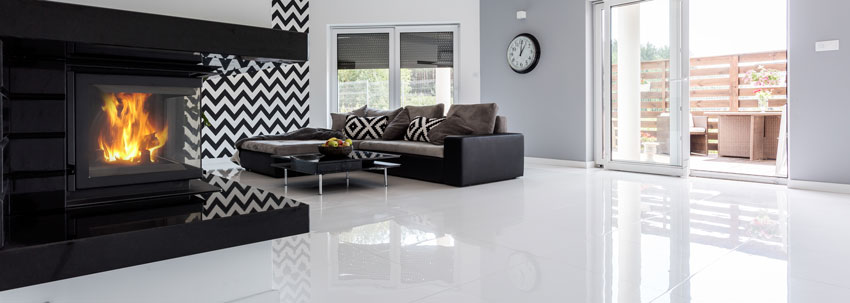salon moderne avec cheminée design, sol blanc brillant et canapé d'angle.