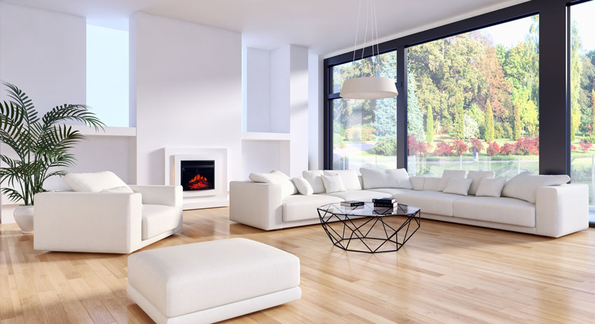 Grand salon avec canapé d'angle blanc, beau parquet marron clair et cheminée électrique.