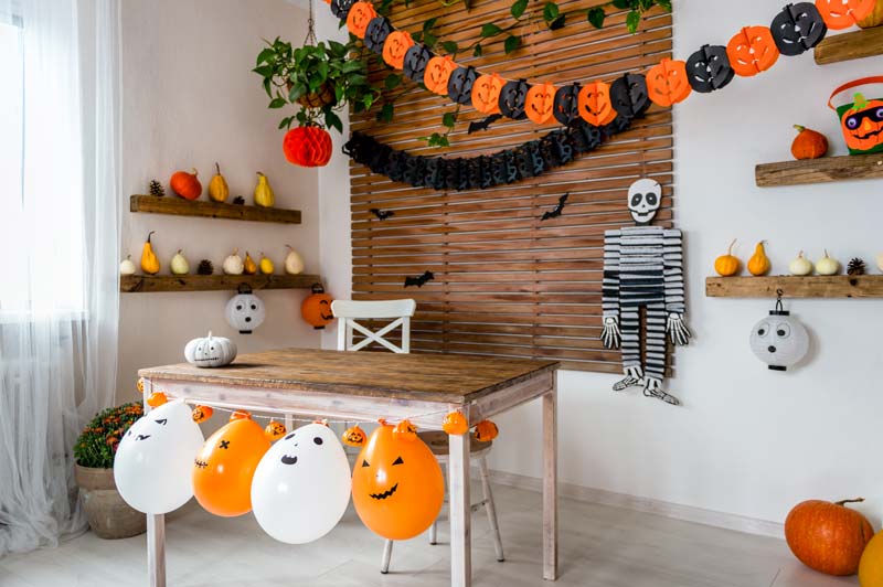 Déco maison Halloween avec ballons et guirlandes noires et oranges.