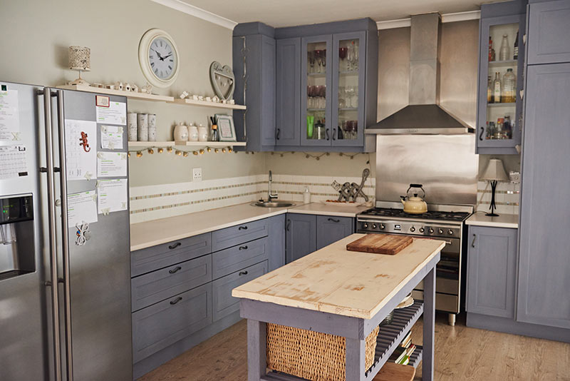 Petite cuisine d'angle grise avec plan de travail en bois clair. 