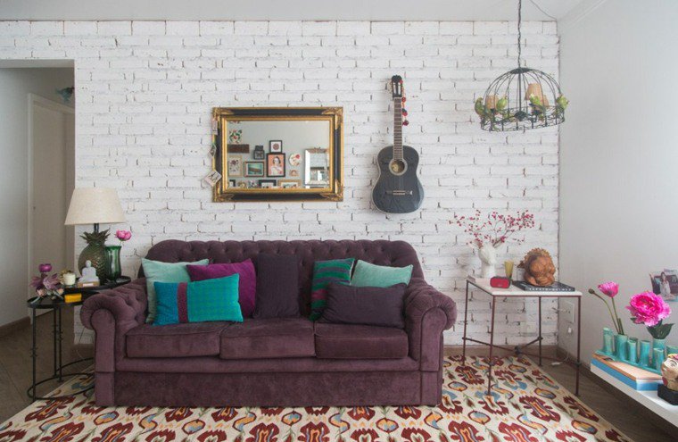 Séjour décoré dans un style bohémien, mur en briques blanches avec guitare accrochée au mur.