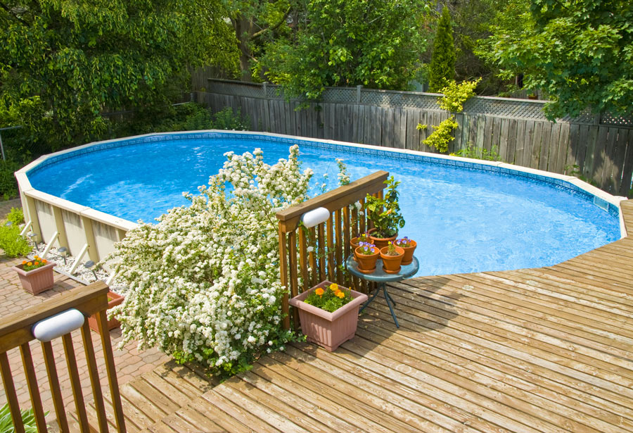 Piscine hors sol installer au bord d'une terrasse dans le jardin.