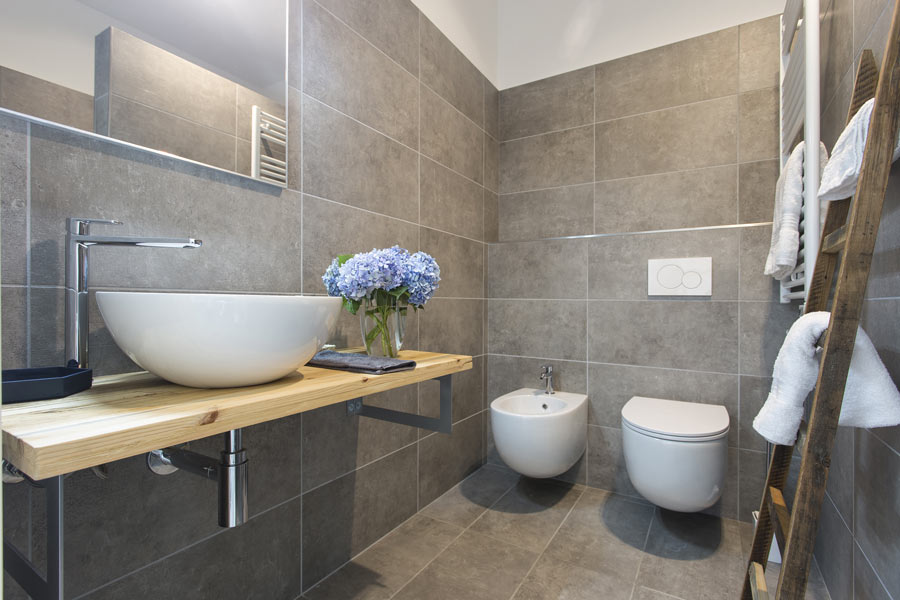 Petite salle de bain moderne avec carrelage gris et sanitaires blancs.