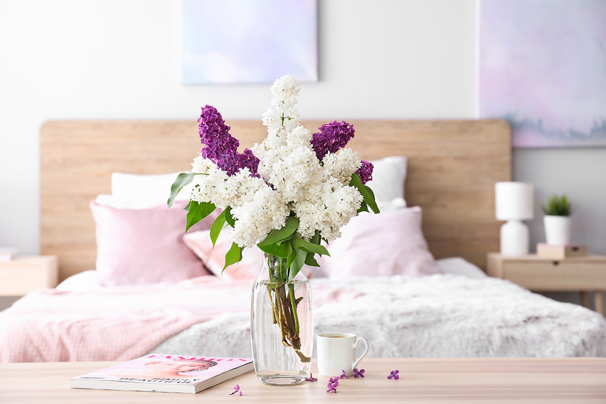 Composition avec des lilas dans un vase dans la chambre à coucher.