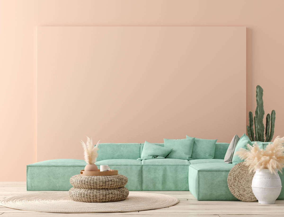 Salon avec des murs roses et un canapé vert pastel.